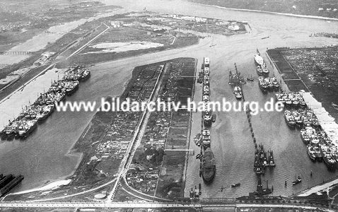 011_15693 - historsiche Luftaufnahme vom Hamburger Hafen mit Blick auf die Waltershofer Hfen ca. 1933; viele Frachtschiffe liegen am Kai, einige an Duckdalben auf Reede in der Mitte des Hafenbeckens. Zur Gelndegewinnung wurde das linke Hafenbecken zugeschttet und wird jetzt als Lagerplatz fr das Containerterminal Eurogate genutzt. Im Hintergrund die Elbe; ganz lks. der Khlbrand.