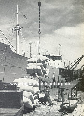 011_15713 - Hafenarbeiter um 1960 im Hamburger Hafen;  von einem Frachter werden per Kran Scke entladen; Arbeiter dirigieren die Last des Kranfhrers an Land; Karren werden fr den Weitertransport verwendet.