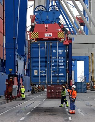 011_15719 - Mitarbeiter des Container Terminals Burchardkai nehmen den grossen Metallcontainer am Kai in Empfang - sie tragen signalfarbene Schutzwesten und Arbeitshelme.