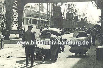 011_157122 - Hamburger Hafenarbeiter beladen ihre Sackkarren und transportieren ihre Last in den Lagerschuppen. 