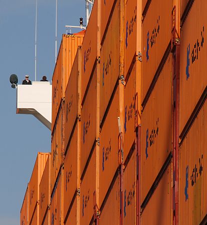 011_15824 - auf dem Containerschiff " Hanover " sind die Container an Deck hoch gestapelt - ein Schiffsoffizier in Uniform blickt vom Ausguck zum Kai.