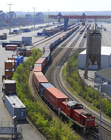 011_17483 - ein langer Zug mit Containern verlsst das Gelnde des Terminals Altenwerder; im Hintergrund die Brcken der Verladestation. 