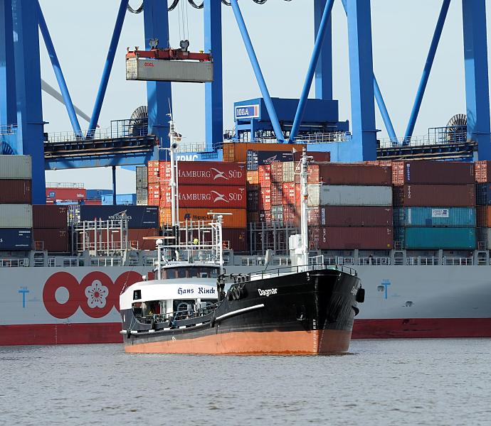 Bilder aus dem Hamburger Hafen - Containerterminal Altenwerder. Tankschiff DAGMAR - Containerschiff, Ladung - Container an der Krananlage. 62_3374 Das Tankschiff DAGMAR wirkt recht winzig neben der Bordwand eines hoch beladenen Contaienrschiffs am Ballinkai des HHLA Container Terminals Altenwerder. Ein Container hngt an der Laufkatze der Krananlage und wird an Land transportiert.