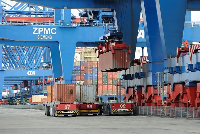 Fotografien vom Hamburger Hafen - Containerverladung AUTOMATED GUIDED VEHICLE. Beladung  eines AGV - HHLA Container Terminal Altenwerder. 77_0170 Auf der Landseite werden die Container vom Laschplatz mit der Portalkatez auf einen der wartenden AGV verladen. Diese automatisierten Transportfahrzeugen wird von der Portalkatze von der Laschplattform aufgenommen und auf der Landseite der Krananlage auf die niedrigen, fhrerlosen Transportfahrzeuge verladen, die den Container an die Lagerblcken bringen. Durch ein im Boden eingelassenes aus etwa 10000 Punkten bestehendes Transpondernetzwerk finden die fhrerlosen AGV ihren Weg zum per Funk bermittelten Bestimmungsort, zustzlich werden sie ber GPS berwacht. Die Flche, auf der die AGV fahren, ist zur Sicherheit fr Personen gesperrt.