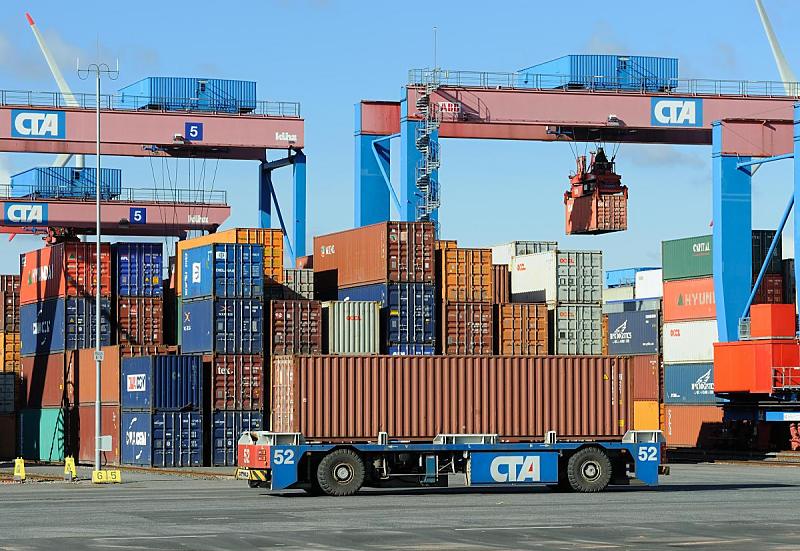 Fotografien von der Arbeit im Hamburger Containerhafen - Betriebsgelnde Containerterminal Automated Guided Vehicles - Containertransport, Portalkrne / Containerlager. 81_0201 Die ca. 75 automatischen Transportfahrzeuge bringen die Container an die Portalkranpaare (Double Rail Mounted Gantry – DRMG), die vor den 26 Lagerblcken stehen - von dort werden die groen Metallbehlter an ihren Bestimmungsort im Containerlager gebracht. Jeder Block umfasst 10 Reihen  37 TEU an jedem Platz knnen vier - in den Auenreihen fnf - Container gestapelt werden. Das DRMG besteht aus zwei unabhngig voneinander arbeitenden Krnen, so dass gleichzeitig die Seeseite mit den AGV und die gegenberliegende Seite mit den Bahn und LKW bedient werden knnen. Durch ihre unterschiedliche Gre knnen beide Krne simultan ber den gesamten Block arbeiten, der kleinere Kran fhrt einfach unter dem greren durch. Fllt einer der beiden aus, kann der Betrieb des jeweiligen Blockes immer noch durch den zweiten Kran aufrechterhalten werden..