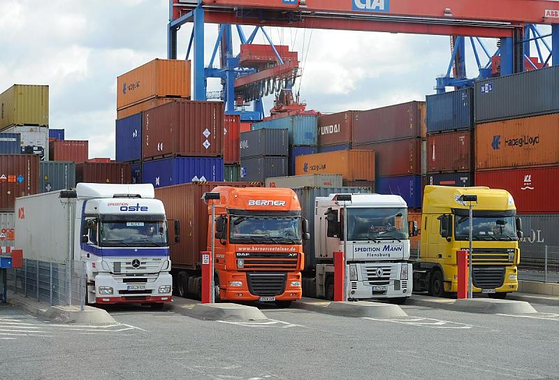 Bilder vom Containerumschlag auf dem HHLA Container Terminal Altenwerder CTA. Sattelkraftfahrzeuge beim Containerlager - Portalkrananlage. 91_0228 TDie Sattelzge sind rckwrts in die Ladebuchten des Altenwerder Containerterminlas eingefahren. Dort nimmt der Portalkran die Metallkiste auf oder ldt einen der Container zum Weitertransport auf den Sattelanhnger.