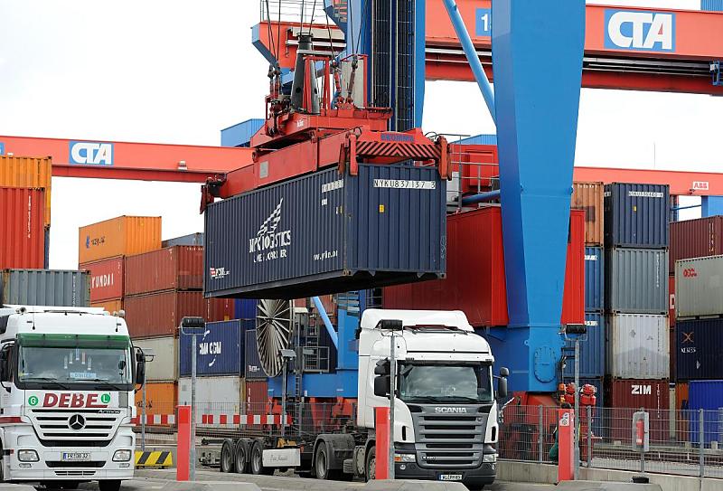 Foto vom Gterumschlag - Hamburger Hafen, HHLA Container Terminal Altenwerder CTA. >Beladung eines Sattelschleppers  - Container im Spreader. 92_0259 Ein 40 Fuss Container ist mit dem Portalkran aus dem Containerlager des Terminals Altenwerder zur Ladezone transportiert worden. Dort warten Sattelkraftfahrzeuge auf ihre Ladung - der Container wird auf dem Containerchassis abgesetzt und verriegelt.