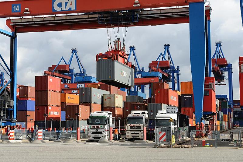 Foto vom Gterumschlag - Hamburger Hafen, HHLA Container Terminal Altenwerder CTA. Beladung der Sattelauflieger  - Container unter dem Kranportal.  93_0241 Die Containerkrne beladen die Sattelauflieger fr den Weitertransport mit ihrer Fracht. Die Beladung der Sattelzge durch die Double Rail Mounted Gantry – DRMG / Portalkranpaare ist der erste Vorgang auf dem Betriebsgelnde des Terminals Altenwerder, der nicht automatisiert ist; von Fernsteuerpltzen im Betriebsgebude aus wird das Beladen der LKW gesteuert.