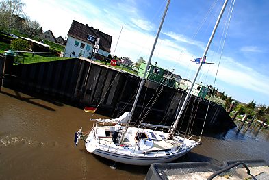 011_15468 -ein Segelboot mit Deutschlandfahne am Heck durchquert das alte Estesperrwerk bei Cranz und fhrt Richtung Elbe; die Fussgngerbrcke ist zur Seite gedreht worden.