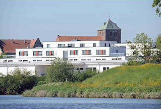 074_4793 Blick ber die Schwinge nach Stadt. Am Ufer des niederschsischen Flusse weisse Neubauten, dahinter die historische St. Wilhadi Kirche. Die gotische Kirche  wurde nach dem Bischof Willehard benannt, der als Missionar in Friesland und Sachsen aktiv war und heilig gesprochen wurde.