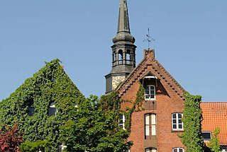 080_8074 Backstein- Speicher- gebude am Ufer des Stader Stadthafens - unter dem Dach befindet sich ein Winde, mit der die Ware auf die einzelnen Speicherbden transportiert werden kann. Die Fassaden der Gebude sind mit Efeu bewachsen. Dahinter der Barockturm der St. Cosmae Kirche.   