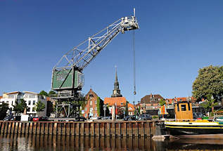 083_8073 Hafenkai von Stadt, ein Rollkran steht am Hafenrand; im Hintergrund Wohnhuser und ehemalige Speichergebude. Rechts das Heck mit der Ruderanlage des 1902 in Itzehoe gebauten und jetzt restaurierten Kstenfrachters "DORA VON STADE".