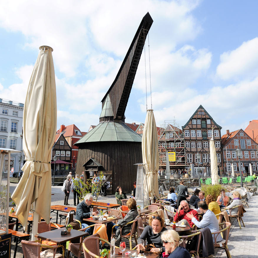 3588 Sonnentag in Stade - Caf mit Tischen und Sitzpltzen auf dem Fussweg - historischer Holztretkran / Alter Kran am historischen Hansehafen.