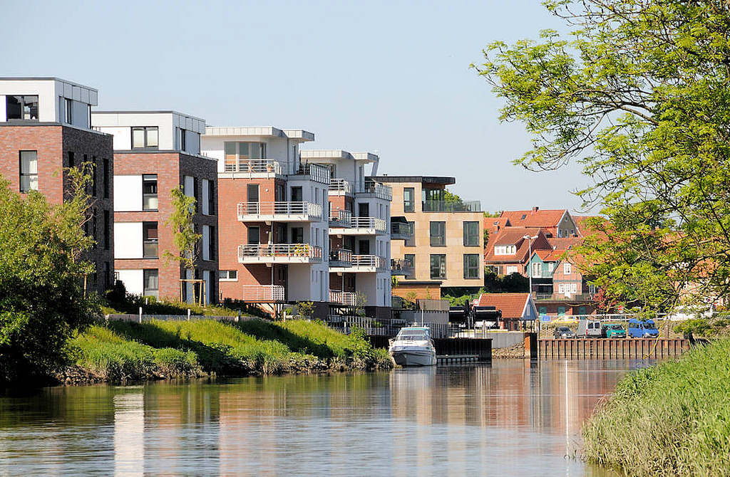 8064 Moderne Wohnungen am Ufer der Schwinge in Stade - Neubauten mit Balkon zum Wasser - Bootssteg mit Sportboot; im Hintergrund der Stader Hafen.