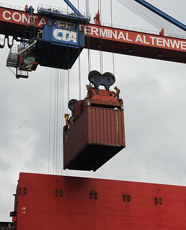 011_17459 - Fotos vom Hamburger Hafen. ein Container wird gerade von der Containerbrcke in die geffnete Ladeluke eines Frachters herunter gelassen. Auf dem Brckenausleger steht der Schriftzug Containerterminal Altenwerder und die Abkrzung CTA.