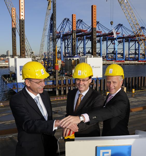 11_21448 Gemeinsam starten Emanuel Schiffer, Vorsitzender der Gruppen- geschäftsführung von EUROGATE, Jens Meier kaufmännischer Geschäftsführer der Hamburger Port Authority HPA und Axel Gedaschko Senator für Wirtschaft und Arbeit den Baubeginn zur Erneuerung der Kaianlagen am Container Terminal EUROGATE. Im Hintergrund treibt die Ramme einen Stahlarmierung in den Hafengrund. ©www.pressefotografie-hamburg.de Erster Rammschlag Bauarbeiten Predöhlkai, Terminal EUROGATE