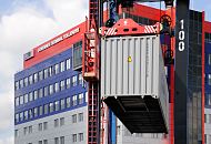 11_05_0558 Ein Vancarrier, auch Portalhubwagen genannt, hat einen Container angehoben - im Hintergrund das Verwaltungsgebude der HHLA mit dem Schriftzug ContainerTerminal Tollerort. Van Carrier und Gebude sind in den typischen HHLA-Farben Blau / Rot gehalten.