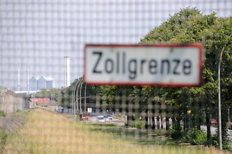 Bilder vom Hamburger Hafen + Freihafen Hamburg. Zollzaun am Spreehafen / Schild "Zollgrenze. Hamburgfotografie von Christoph Bellin.  53_9332 Hinter dem Zollzaun verluft die Harburger Chaussee im Hamburger Stadtteil Wilhelmsburg - im Hintergrund die Schornsteine und Betriebsgebude vom Heizkraftwerk in Tiefstack.