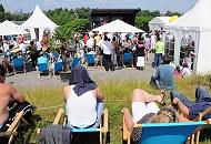 58_9317 Wilhelmsburger und Brger der Veddel hren der Rede zu die die Politiker anlsslich der Zollzaunffnung am Spreehafen halten. Einige sitzen in Liegesthlen auf dem Deich in der Sonne. 