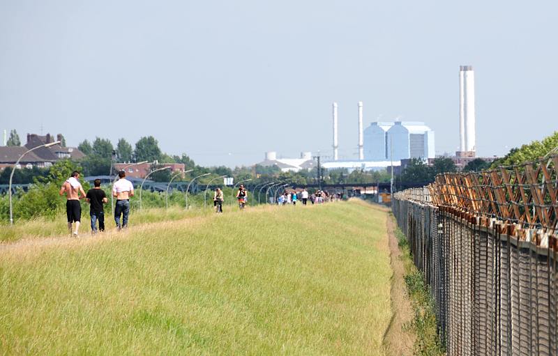 Bilder vom Hamburger Hafen / Spreehafen. Spaziergnger nach ffnung des Zollzauns am 04.07.10 auf dem Deich.Hamburgfotograf Christoph Bellin.  61_9335 SpaziergngerInnen und RadfahrerInnen nutzen die Zollzaundurchlsse um die neu erschlossene Freizeitflche zu erkunden. Rechts der Zollzaun der das 13 Hektar grosse Gebiet am Spreehafen von der Nutzung durch die Anwohner abgetrennt hat. Im Hintergrund das Heiskraftwerk Tiefstack.