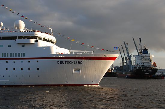 011_15688 - das Kreuzfahrschiff Deutschland verlsst den Hamburger Hafen; im Hintergrund ein Frachter am Kai und Hafenkrne, die das Schiff entladen. 