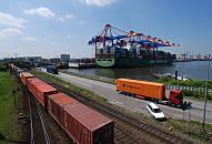 11_21388 Blick ber den Waltershofer Hafen zum Container Terminal EUROGATE - ein Containerschiff liegt am Predhlkai, die Ausleger der Containerbrcken sind herunter gefahren; der Frachter wird mit Container beladen oder die Ladung wird gelscht. Im Vordergrund fhrt ein langer Containerzug, auf der Strasse im Hamburger Hafen transportieren Lastkraftwagen Container auf Tieflader.  www.bildarchiv-hamburg.de