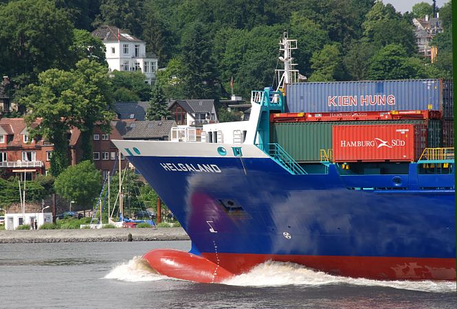 11_21393 Der Container Feeder HELGALAND luft aus dem Hamburger Hafen aus. Container stehen auf dem Vorderdeck des Frachters - das Schiff scheint nicht voll beladen zu sein, da der Wulstbug und die markierte Wasserlinie gut zu erkennen sind. Im Hintergrund Huser vom Hamburger Stadtteil Blankenese.  www.bildarchiv-hamburg.de