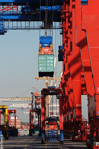 11_21404 Ein Container wird mit dem Containergreifer der Containerbrücke von der Laschplattform, wo die Transportsicherungen von den Lascharbeitern entfernt auf den Boden gestellt. Auf der Kaianlage des Predöhlkais vom Container Terminal EUROGATE warten die von Fahrern gesteuerten Portalhubwagen, die die Stahlkisten an ihren Lagerplatz transportieren werden. ©www.bildarchiv-hamburg.de