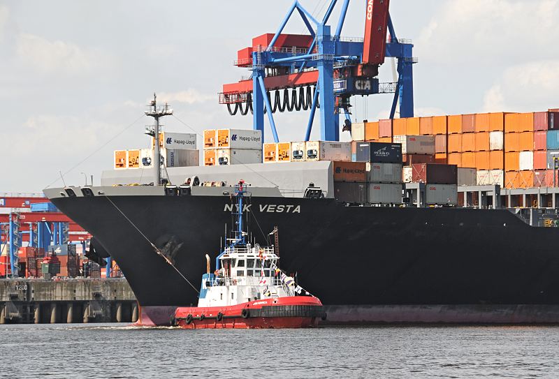 Bilder von Schiffen im Hamburger Hafen : Schlepper und Schiffsbug der NYK VESTA  033_8005_0509 DEin Schlepper zieht den Schiffsbug des Containerfrachters NYK VESTA von der Kaianlage des HHLA Container Terminals Altenwerder. Auf mehreren Ebenen sind die Metallboxen auf dem Deck des Frachters gestapelt - die NYK VESTA kann ca. 8600 Standart-Container transportieren und hat ihren Heimathafen in Panama.  www.hamburg- fotos.org