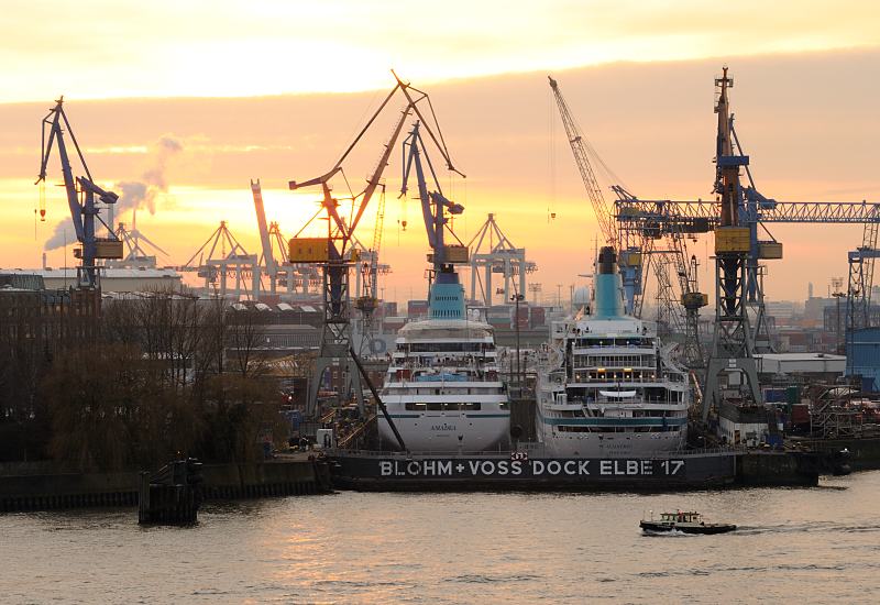 Bilder aus der Hansestadt Hamburg - Kreuzfahrtschiffe AMADEA + ALBATROS, Sonnenuntergang. 03_44357 Sonnenuntergang im Hamburger Hafen - die Sonne geht hinter den Krnen der Werft Blohm + Voss unter - zwei Kreuzfahrtschiffe liegen im Trockendock Elbe 17 fr Wartungsarbeiten nebeneinander. Eine Barkasse fhrt Richtung Reiherstieg - das Schiff hat in der Dmmerung seine Positionslaternen gesetzt. www.fotograf-hamburg.de