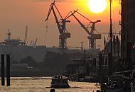 10_26040 Blick über den Sandtorhafen, dem Hamburger Traditionsschiffhafen zur Elbe - Barkassen fahren in der Abenddämmerung über das Wasser. Der Himmel ist rot gefärbt - Kräne stehen auf der gegenüberliegenden Seite des Flusses.  