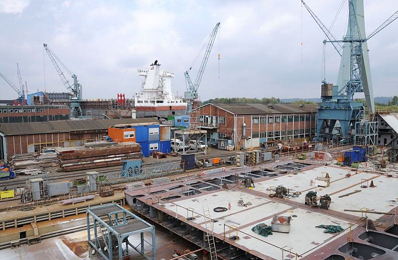 Fotografien von Hamburger Hafen und Werften   Schiffswerft Hamburg Neuenfelde. Fotoleinwand + Hamburg-Poster von Hamburgbildern als Geschenk zum Jahrestag - Jubilum - Firmenabschied.  39_5191 Blick ber die Sietas-Werft in Hamburg Neuenfelde. Im Vordergrund liegt ein halbfertiges Schiffssegment, whrend hinter den Arbeitshallen die frisch gestrichenen Aufbauten ein Schiffsneubaus zu erkennen sind. www.fotos- hamburg.de