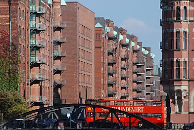 01_15785 - ein roter Doppeldeckerbus der Hamburger Stadtrundfahrt mit Touristen auf seiner Fahrt durch die Speicherstadt - im Hintergrund die Kupfergiebel der historischen Lagerhuser des ehem. Hamburger Freihafens. 