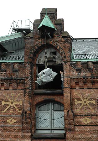 01_15789 - Ballen mit Teppichen sind auf dem obersten Boden des Lagerhauses ange- kommen und werden von einem Mitarbeiter in Empfang genommen. 