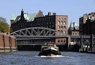 11_17543 Hamburg Fotos - Bilder der Hansestadt Hamburg_ eine Barkasse der Hamburger Hafenrundfahrt fhrt mit Hamburg Touristen im Zollkanal, der ehemalige Zollgrenze am Freihafen bei der Hamburger Speicherstadt. Die Kibbelstegbrcke fhrt ber den Kanal zur Hamburger Hafencity.  In der Bildmitte das Speichergebude H, rechts ein Teil vom Lagergebude E und dazwischen der kupfergedeckte Turm vom ehem. Direktionsgebude der HHLA.