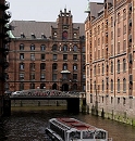 11_17548 ein Schiff der Hafenrundfahrt kommt vom Kleinen Fleet und fhrt im Wandrahmsfleet - an Bord Hamburg Touristen, die sich die Sehenswrdigkeiten der Hansestadt Hamburg ansehen. Die Barkassen sind so flach gebaut, damit sie auch bei Flut die vielen Brcken in Hamburg passieren knnen. Im Hintergrund die Kannengiesserortbrcke und das Speichergebude Q.