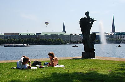 011_15678 - lauf einer Wiese an der Binnenalster liegen Hamburger in der Sonne in der Bildmitte die Jacobi Kirche, lks. davon ein Heissluftballon und ganz rechts die St. Petri Kirche 