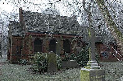 Kapellenansicht mit steinernem Grabkreuz