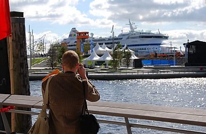 011_15762 - ein Besucher der Hafencity fotografiert vom Dalmannkai aus zum Marco - Polo - Platz; auf dem orangefarbenen Aussichtsturm / view point stehen Hamburg Touristen und sehen sich die Umgebung an. im Hintergrund liegt ein Kreuzfahrtschiff am Terminal. 