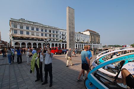 011_15613 - Touristen fotografieren auf dem Rathausplatz; in der Bildmitte die Barlachstele; re. warten die Chauffeure modernerner Fahrradrikschas auf Fahrgste. 