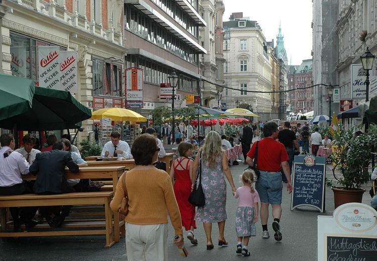 11_18976 Die Colonnaden als Hamburger Prachtboulevard mit der interessanten Neorenaissance - Architektur der Grnderzeit ist eine attraktive Sehenswrdigkeit fr Hamburg Touristen. Als Fussgngerzone wird die Hamburger Einkaufsstrasse gerne zum Shopping besucht. Bei schnem Sonnenwetter knnen die Hamburger und Hamburgerinnen in Strassencafs und Restaurants im Freien sitzen und ihre Mittagspause geniessen. Stellschilder auf dem Weg weisen auf die Speisekarte des Mittagstischs hin. Im Hintergrund sind Gebude vom Jungfernstieg und der Turm des Hamburger Rathauses zu erkennen.  www.bildarchiv-hamburg.de