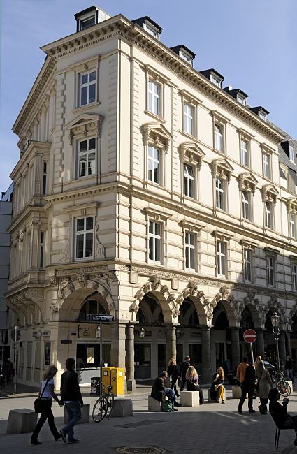 11_18978 Blick ber den Gustav-Mahler-Platz zum Sulengang der Hamburger Colonnaden. Passanten schlendern ber den Platz oder sitzen in der Sonne. An der Strassenecke stehen zwei gelbe Briefksten mit Posthorn. Das historische Etagenhaus war ca. 1880 als Wohngebude errichtet, jetzt befinden sich zumeist dort Bros o..   www.bildarchiv-hamburg.de