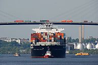 05_15577 Lastwagenverkehr auf der Khlbrandbrcke; ein hoch beladener Containerfrachter fhrt mit Hilfe eines Schleppers auf dem Khlbrand und hat gerade die 53m hohe Hafenbrcke unterquert. Rechts die Faultrme der Klranlage Khlbrand und auf der anderen Seite der Elbe die Wohnhuser an der Palmaille und Elbchaussee von Hamburg Altona. 