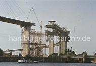 08_15579 Die Khlbrandbrcke wurde 1974 eingeweiht und berquert den 325m breiten Khlbrand. Der Brckenzug ist insgesamt 3618 m lang und die zweitlngste Straenbrcke Deutschlands. Das Bauwerk besteht aus der stlichen Rampenbrcke, der Strombrcke und der westlichen Rampenbrcke. Die stliche Rampenbrcke ist eine 2050 m lange Stahlbeton- und Spannbetonkonstruktion, die 520 m lange Strombrcke ist als Schrgseilbrcke in Stahl ausgefhrt und die 1048 m lange westlichen Rampenbrcke aus Spannbeton. Rechts die Rugenberger Schleuse - die Schleusentore ffnen sich gerade, zwei Schiffe wollen die Schlickschleuse zur Durchfahrt in den Waltershofer Hafen nutzen.