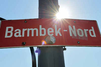 2704 Stadtteilschild - rot mit weisser Schrift, Barmbek Nord am Laternenmast.