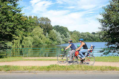 1753 FahrradfahrerInnen auf dem Kupferdamm beim Kupferteich in Hamburg Farmsen; der Kupferteich wird von der Berner Au gespeist - frher wurde dort mit Hilfe eines wasserbetriebenen Kupferhammers z. B. Kupferdraht hergestellt.