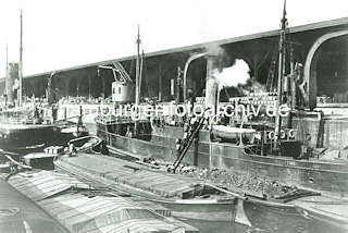 X4588932_19 Ein Dampfer bunkert am Dalmannkai im Hamburger Hafen Kohle; Kohlentrger tragen Kiepen mit Kohle ber eine Leiter von der beladenen Schute auf das Dampfschiff im Grasbrookhafen.