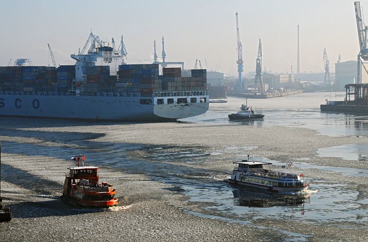11_22730 Winter in Hamburg; Eisgang auf der Elbe und im Hamburger Hafen. Ein Containerschiff wird von einem Schlepper rückwärts in das Hafenbecken vom Tollerort Terminal gezogen. Hoch ragen die Arme der Hafenkräne in den diesigen Winterhimmel. Eine Hafenfähre bahnt sich ihren Weg durch das Eis auf der Elbe und steuert den Anleger "Dockland" an. ©www.fotograf-hamburg.de  Hamburg-Bilder  - Eisgang auf der Elbe / Hafen 