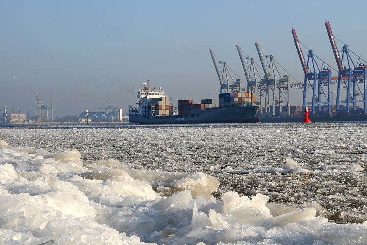 Hamburger Winterbilder  - Eis auf der Elbe, Containerschiff in Fahrt.  11_22734 Auf der Elbe schwimmt dichtes Eis, das auch das Ufer des breiten Hamburger Flusses bedeckt. Das beladene britische Containerschiff Maike D. fhrt flussabwrts durch das Eis. Die Containerbrcken am Athabaskakai des Container Terminals Burchardkai sind hochgefahren - es liegt kein Frachter an den Kaianlagen. Die signalrote Tonne begrenzt die Fahrrinne fr die grossen Schiffe auf der Elbe. www.fotograf-hamburg.de