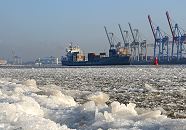 11_22734 Auf der Elbe schwimmt dichtes Eis, das auch das Ufer des breiten Hamburger Flusses bedeckt. Das beladene britische Containerschiff Maike D. fhrt flussabwrts durch das Eis. Die Containerbrcken am Athabaskakai des Container Terminals Burchardkai sind hochgefahren - es liegt kein Frachter an den Kaianlagen. Die signalrote Tonne begrenzt die Fahrrinne fr die grossen Schiffe auf der Elbe. www.fotograf-hamburg.de